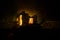 Old stone house burning uncontrollable in the night. A fire in a country house. Creative artwork decoration