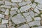 Old stone pavement texture with grass. Granite cobblestones pavement background