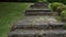 Old stone ruined staircase in the garden with grass and ornamental shrub