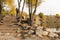 Old stone stairs in autumn. Staircase in steps among yellow foliage and big rocks.