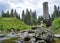 Old stone tower above a stream with boulders at a place of a broken dam