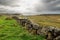 Old stone wall and excellent example of old masonry craft. West coast of Ireland. Atlantic ocean, Beautiful cloudy sky. Sun flare