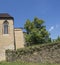 Old stone wall, gothic facade with window, green tree and blue sky background