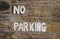 Old stone wall White No Parking Hand Painted Sign in England