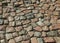 An old stoneblock pavement cobbled with natural stone blocks with gaps between blocks