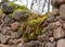 Old stones overgrown with moss and lichens, stone wall from old castle ruins, autumn in the park