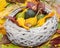 Old straw basket filled with baby pumpkins on the autumn colored leaves