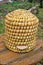 Old straw beehive standing on a wood table outdoors