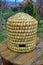 Old straw beehive standing on a wood table outdoors