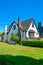 Old style family house with lawn and hedgerow in front on blue sky background