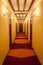 Old style hotel hallway with wooden brown doors, reddish carpet, and yellow walls