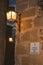 Old style metal sconce stuck to the stone wall and soft light at dusk in Caceres