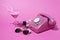 Old style rotary telephone on pink background with cocktail, sunglasses and nail polish