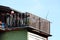 Old suburban family house balcony with dilapidated wooden fence filled with various stuff and plants