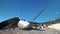 An old sunken broken yacht lies in pile of scrap metal near rock on the seashore