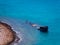 Old sunken ship near the rocky shore - beautiful blue water