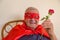 Old super hero holding red rose