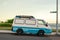 Old surfing van with surfboards on a roof rack with beach and surf in the background