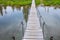 Old suspension bridge top view against the background of blue water and green shore. Horizontal photo of architectural