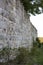 Old tall medieval stone castle wall overgrown with plants