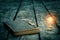 Old tattered book on a wooden table. Reading by candlelight. Vintage composition. Ancient library.