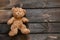 an old teddy brown bear lies on a burnt wooden floor alone, a child's toy