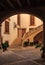 Old terracotta colored courtyard with a large staircase seen through a dark archway in a residential neighborhood in Palma