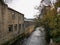 Old textile mill by the river with trees on the other bank in Huddersfield