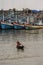 Old Thai Woman paddles wooden boat in fishing harbor