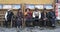 Old tibetan people in traditional clothes sit on a bench nearby Jokhang temple