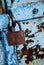 Old tinny garage door with shabby blue paint and a rusty padlock