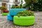 Old tires that are painted in assorted colors and used for a flower planter, modern garden