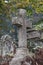 Old tomb in the cemetery with a cement cross, plants between the graves in the cemetery