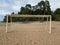 old torn football goal on empty sandy beach.