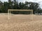 old torn football goal on empty sandy beach.