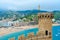 Old tower and stone fortress walls against background of resort town of Tossa de Mar, sea and mountains, Spain
