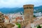 Old tower and stone walls against background of resort town of Tossa de Mar and mountains, Spain