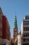 old tower with tall spire and historical buildings on street