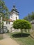 Old town hall tower in castle park Benatky nad Jizerou with footpath, stair, green trees, sunny summer day, blue sky background