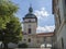 Old town hall tower in castle park Benatky nad Jizerou with footpath, stair, green trees, sunny summer day, blue sky background