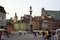 Old town square buildings lit by the sun in a row, people in the market square bronze column of King Sigismund statue sculpture