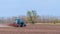 An old tractor in the field plows the land. Spring landscape of a countryside, a farm