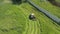 Old tractor mows green ripe grass in a meadow - aerial drone shot