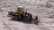 Old Tractor on Rubber Wheels Moves Sand Using a Bucket on Construction Site