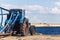 Old tractor with trailer stands on shore of sea bay.