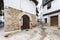 An old traditional house with stone archway at the front door and granite stone facade with some small potted plants outside in