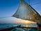Old traditional maritime traditional vessel Dhow boat sailing under torned sail in the open Indian ocean near Zanzibar island in
