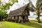 Old traditional thatched yapese men`s meeting house faluw or fale, on an elevated limestone platform with bank of rai stone money