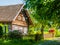 Old traditional timbered cottage with romantic and idyllic lush green flower garden with wooden fence on sunny summer