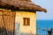 Old traditional white croft cottage with thatched roof, with sea in the bay. Concept of isolated beauty, conservation, building wi